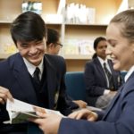 Girl and boy student holding a book and laughing
