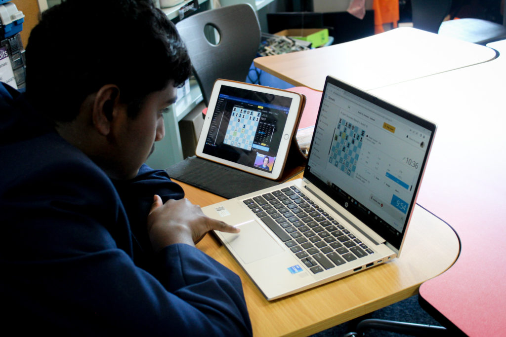 A student is concentrating on a game of online chess. He is using a laptop