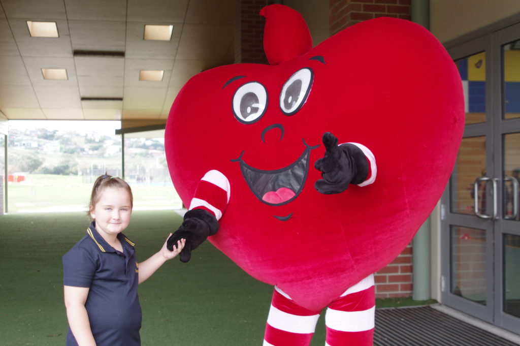 Girl holds hand of costumed heart character