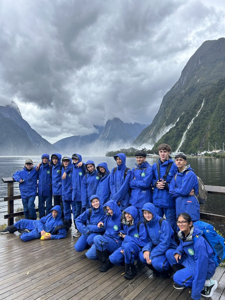 Students in blue jackets in front of lake