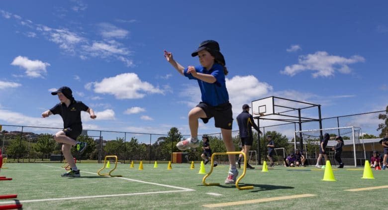 Two students jumping over little hurdles