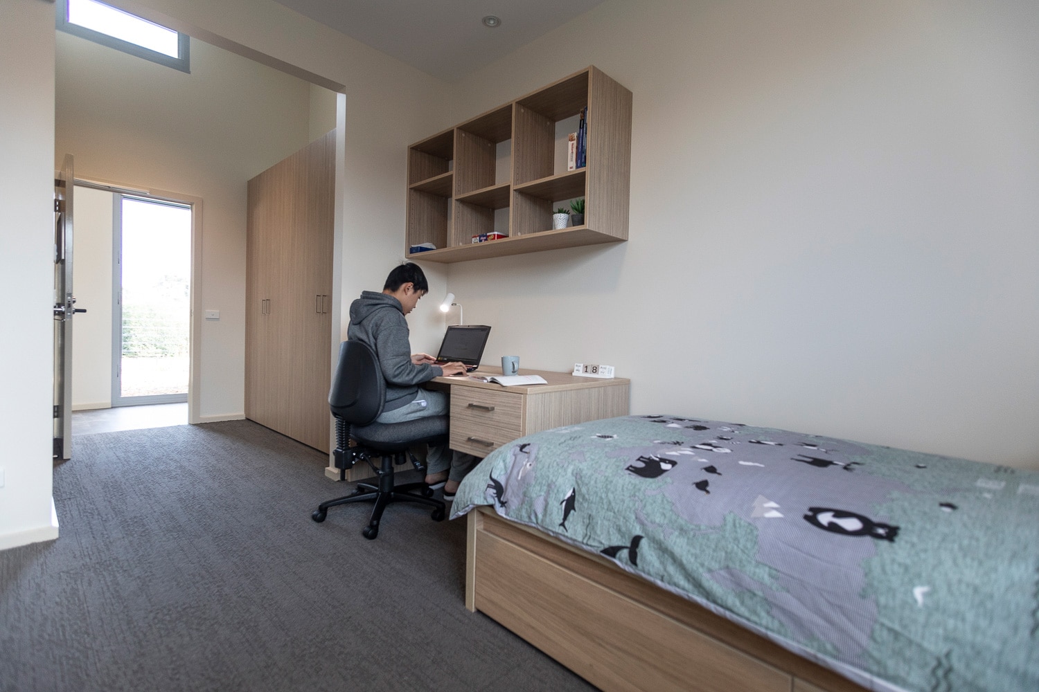 Internation student studying in boarding house bedroom